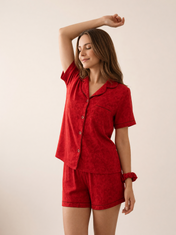 Mujer con pijama Esencia Floral Amore Rojo de algodón Pima, de perfil en estudio. Imagen generada con IA sobre la prenda real.