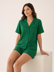 Mujer sentada con pijama Esencia Floral Amore Verde de algodón Pima, en estudio. Imagen generada con IA sobre la prenda real.