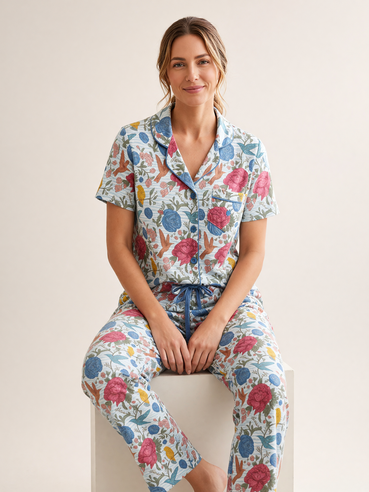 Mujer sentada con pijama Jardín Eterno Donna Listado de algodón Pima, en estudio. Imagen generada con IA sobre la prenda real.