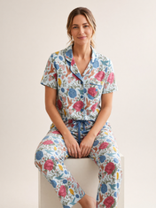 Mujer sentada con pijama Jardín Eterno Donna Listado de algodón Pima, en estudio. Imagen generada con IA sobre la prenda real.