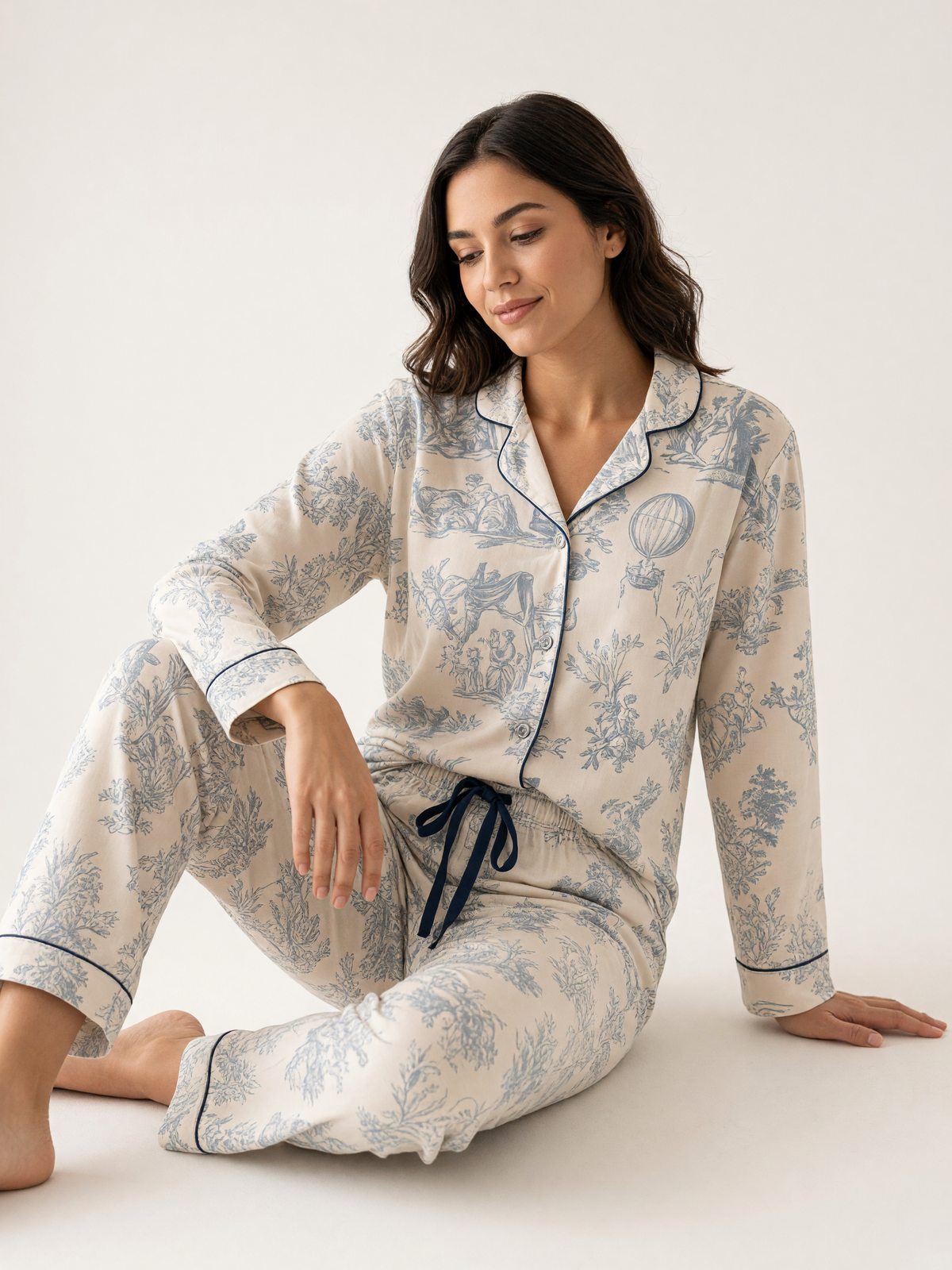 Mujer sentada con pijama Sueños en Vintage Armonía Polvo Azul de algodón Pima, en estudio. Imagen generada con IA sobre la prenda real.